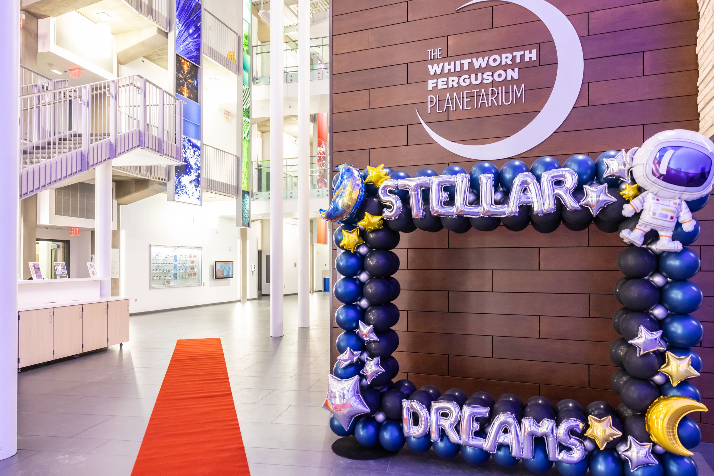 A red carpet leads to a Stellar Dreams balloon arch under the Whitworth Ferguson Planetarium sign